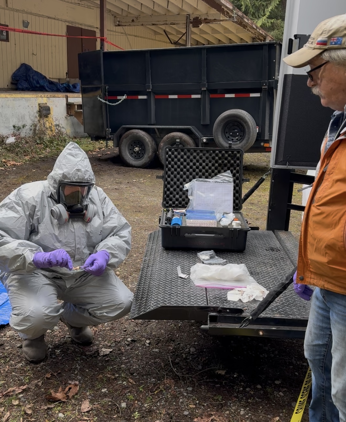 Ecology spills responder in hazmat gear kneeling while conducting flammability testing on a sample collected during the cleanup operations.